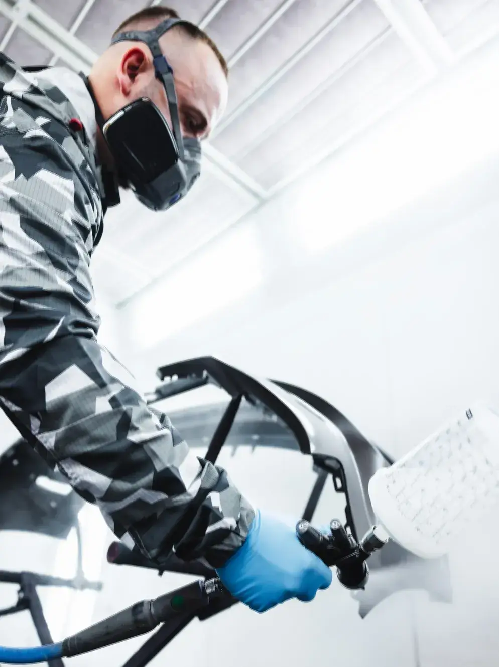 Fachmann beim Lackieren eines Stoßfängers in der Lackierkabine – professionelle Autolackierung bei Karosserie Blanke