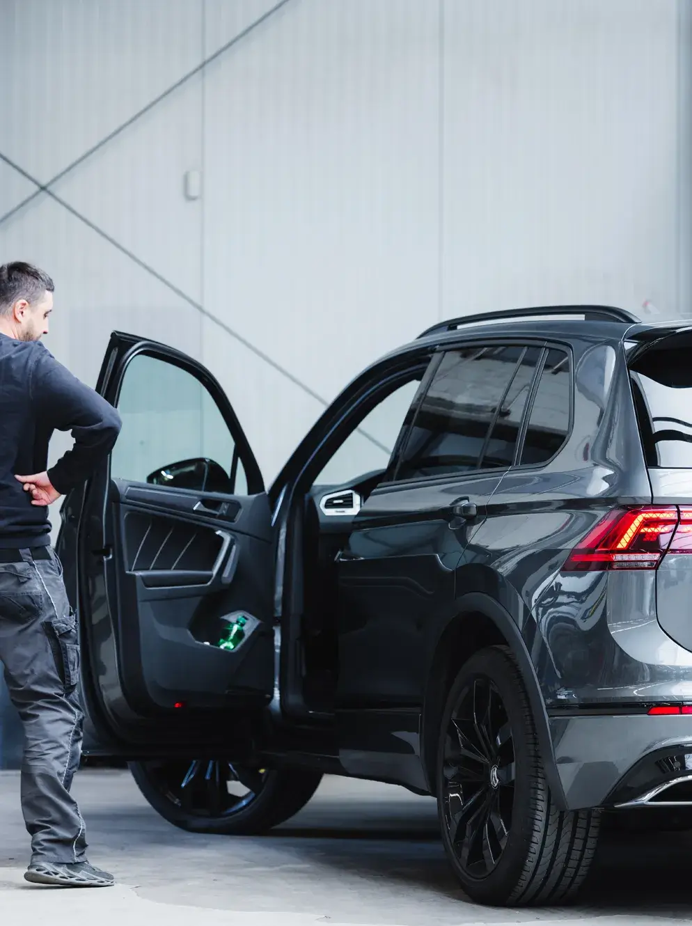 Mitarbeiter von Karosserie Blanke bei der abschließenden Kontrolle eines dunklen SUV mit geöffneten Türen vor der Übergabe an den Kunden.