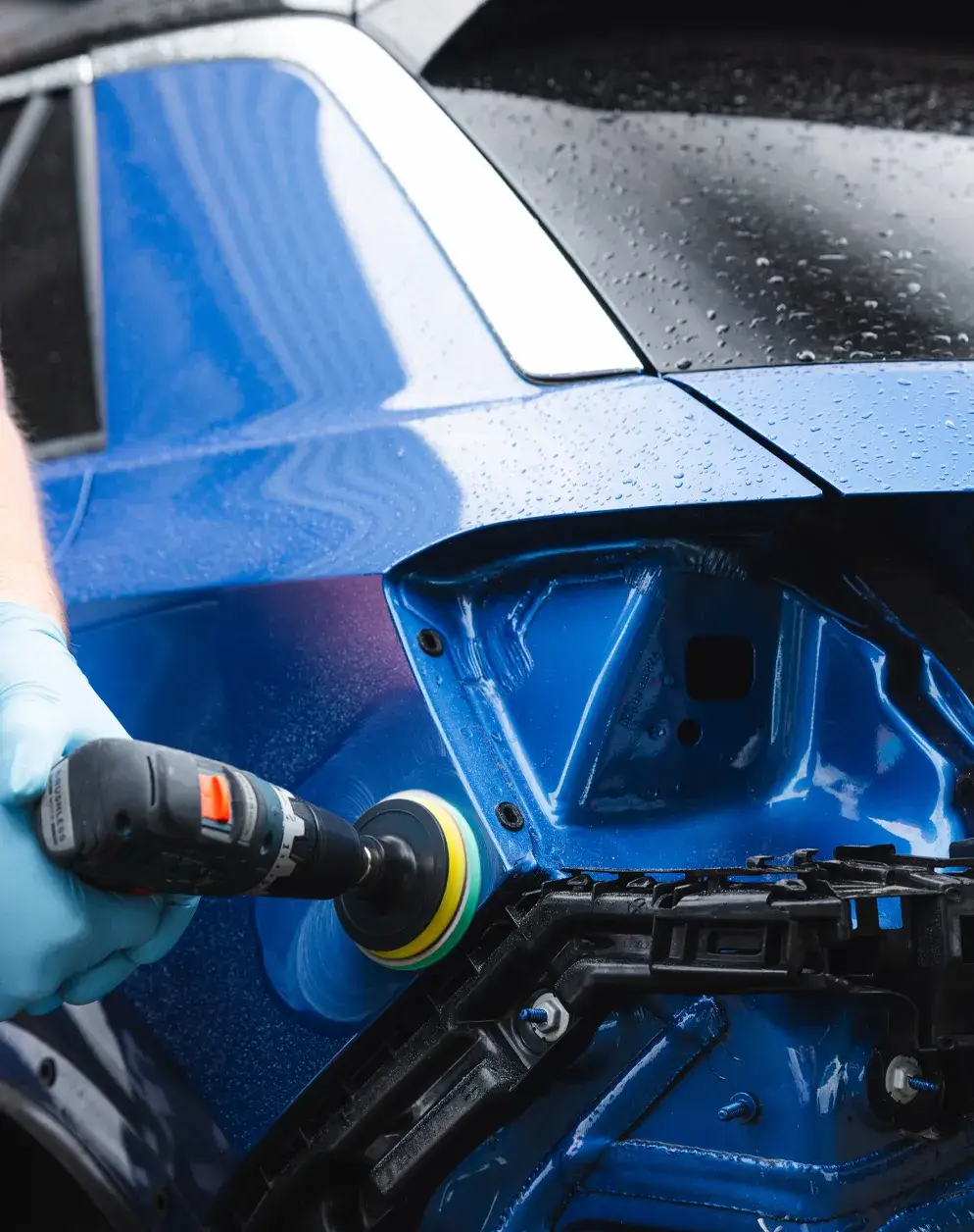 Mitarbeiter poliert die Karosserie eines blauen Fahrzeugs nach einer Reparatur – Karosserie Blanke Bremerhaven