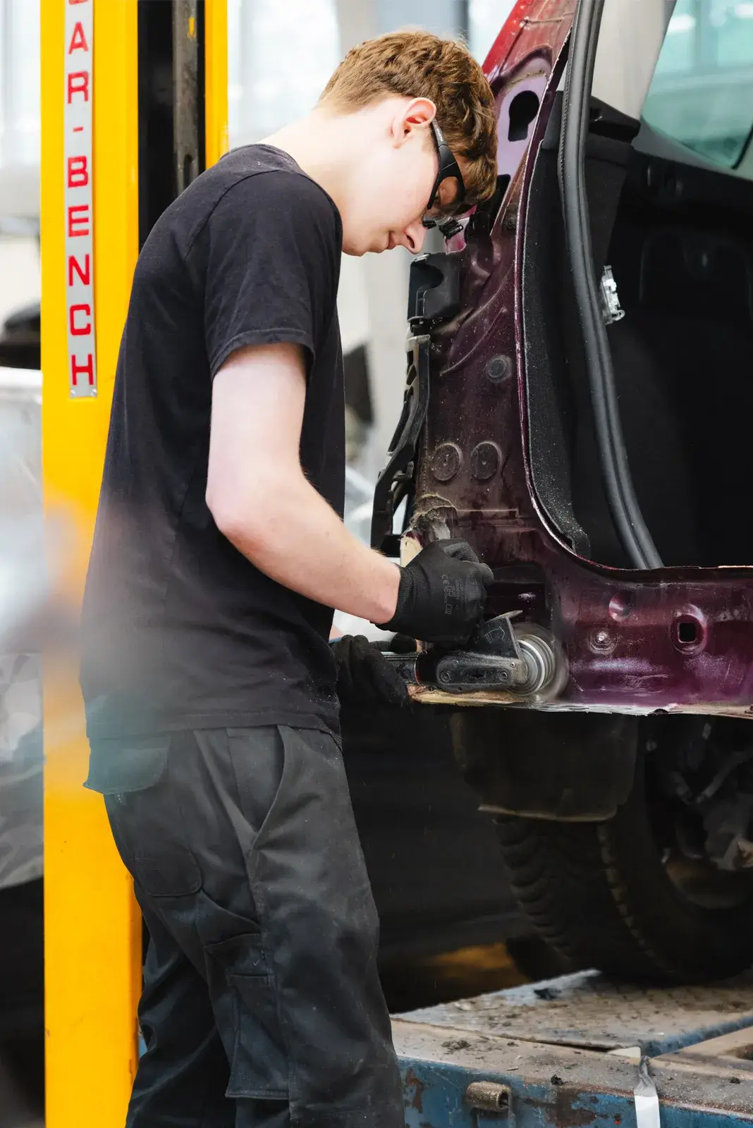 Mitarbeiter bearbeitet den Tür- und Seitenbereich eines Fahrzeugs bei der Karosserieinstandsetzung - Karosserie Blanke Bremerhaven